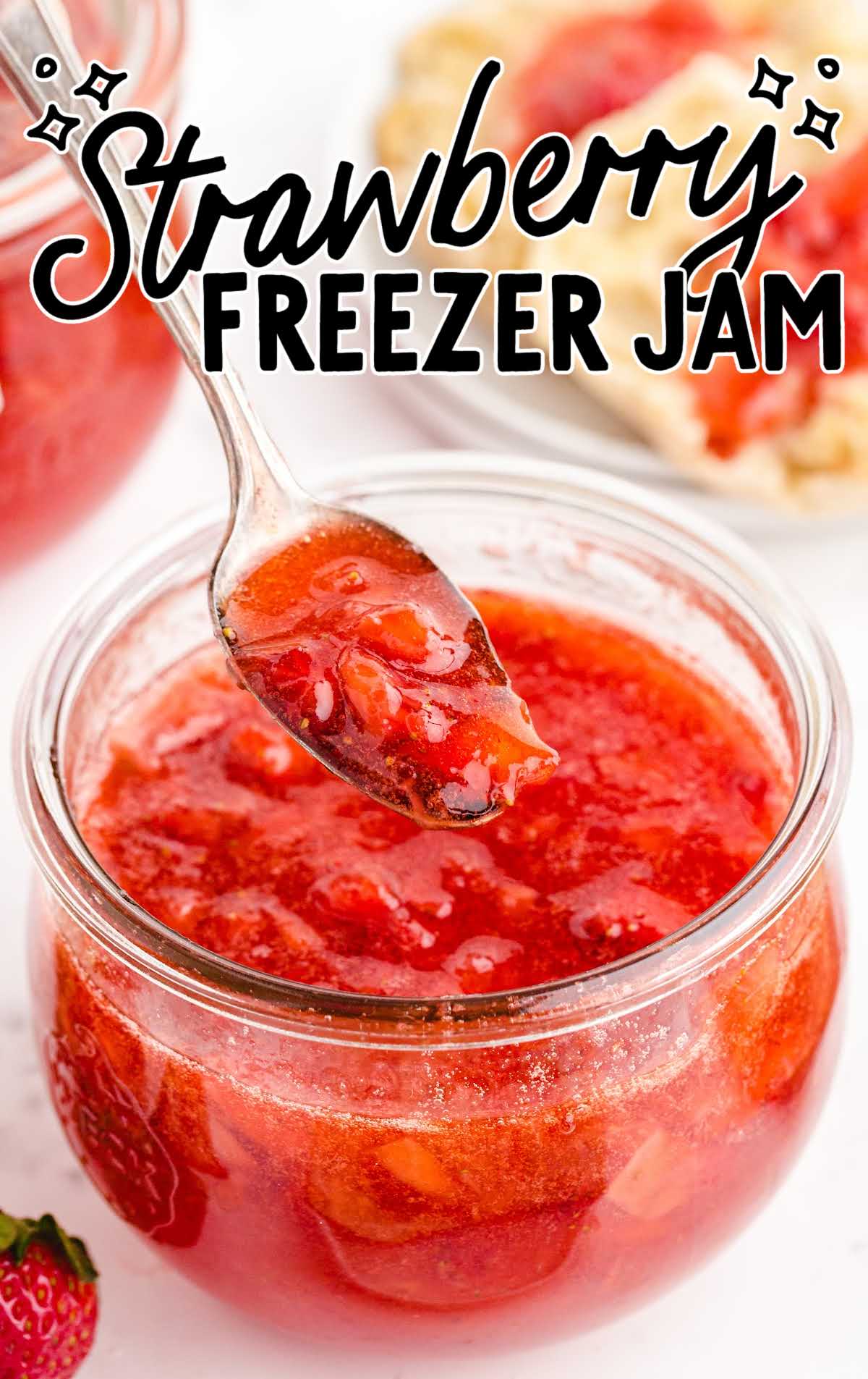 close up shot of a jar of Strawberry Freezer Jam with a spoonful of strawberry jam