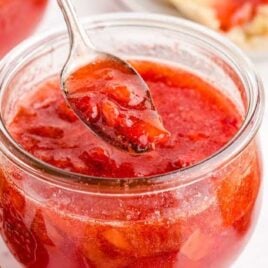 close up shot of a jar of Strawberry Freezer Jam with a spoonful of strawberry jam