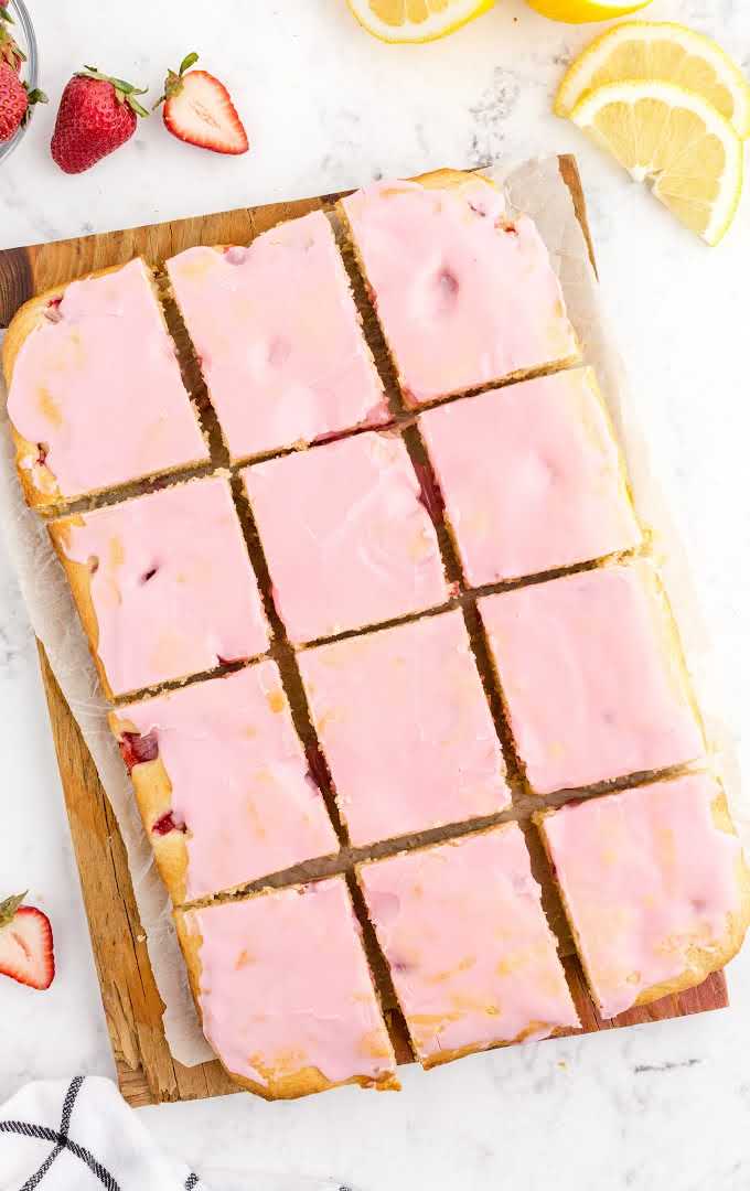close up shot of strawberry lemon blondies with strawberry glazed sliced on a wooden board