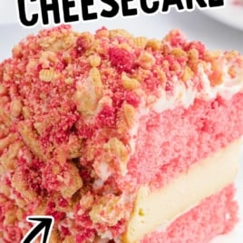 Close-up of a slice of strawberry shortcake cheesecake with cookie topping and cheesecake center, text overlay reads “Strawberry Shortcake Cheesecake – Vanilla & Strawberry Cookie Crumble!”