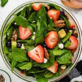 overhead shot of strawberry spinach salad garnished with feta cheese in a bowl