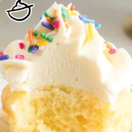 close up shot of a frosted vanilla cupcake topped with sprinkles with a bite taken out of it