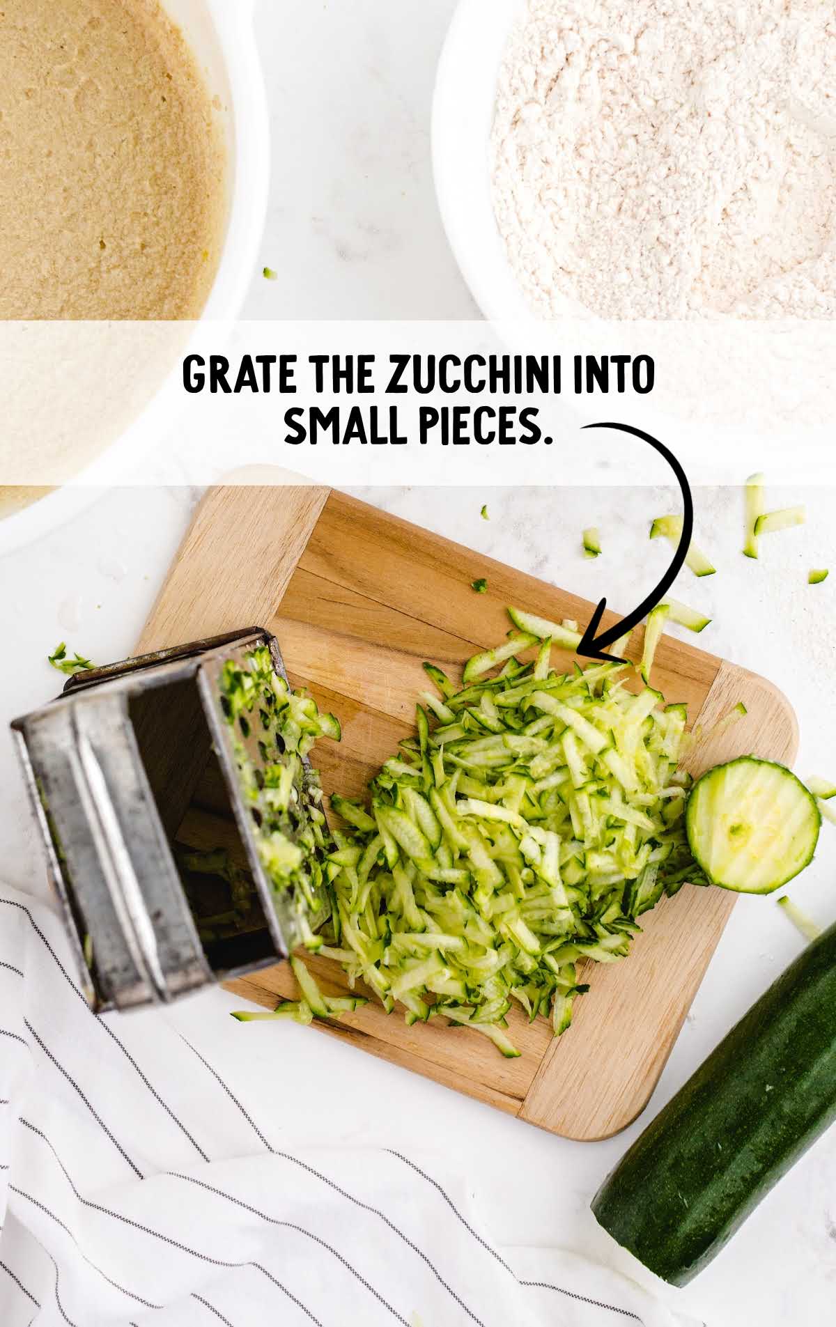 zucchini bread process shot of zucchini grated into small pieces on a wooden board