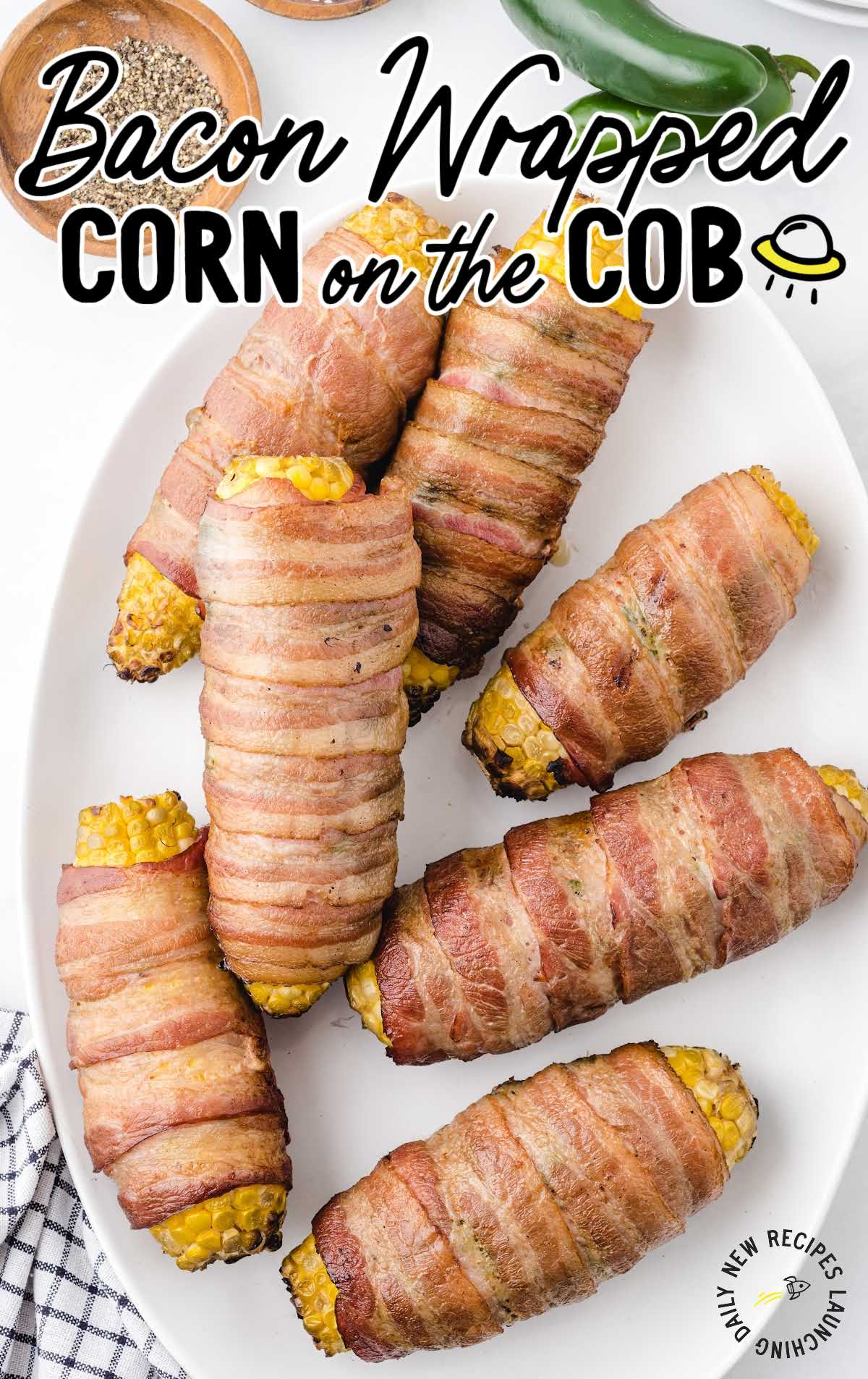 overhead shot of bacon-wrapped corn on the cob on a white plate