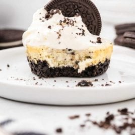 cookies and cream cheesecakes with a Oreo cookie on top on a plate with a piece taken out of it