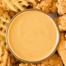 overhead shot of copycat chick fil a sauce in a condiment bowl with chicken tenders and fries