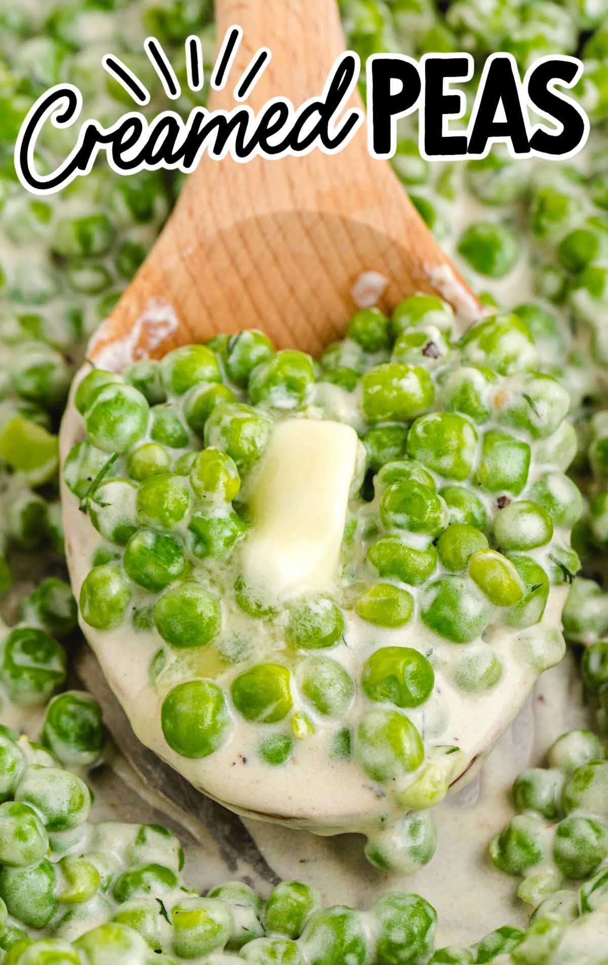 Wooden spoon scooping creamed peas topped with a pat of melting butter.
