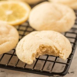 close up shot of lemon sugar cookies with a bite missing on a cooling rack
