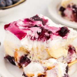 close up shot of a slice of blueberry angel food cake with a piece being taken out with a fork