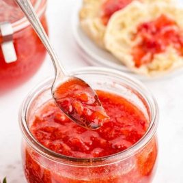strawberry freezer jam in a glass jar with a spoon