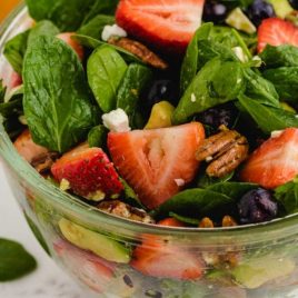 close up shot of strawberry spinach salad garnished with feta cheese in a bowl