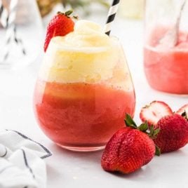 close up shot of wine slushies in a cocktail glass with strawberries and a straw