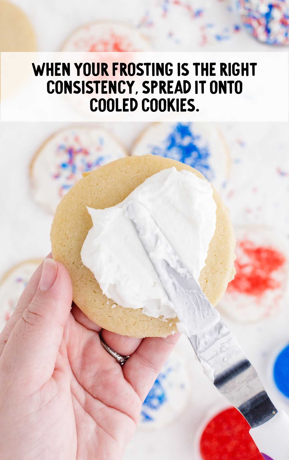 frosting being spread onto a sugar cookie