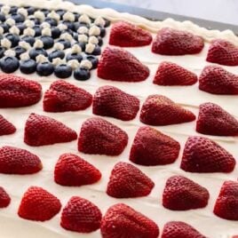 close up shot of American flag cake topped with strawberries and blueberries in a baking dish