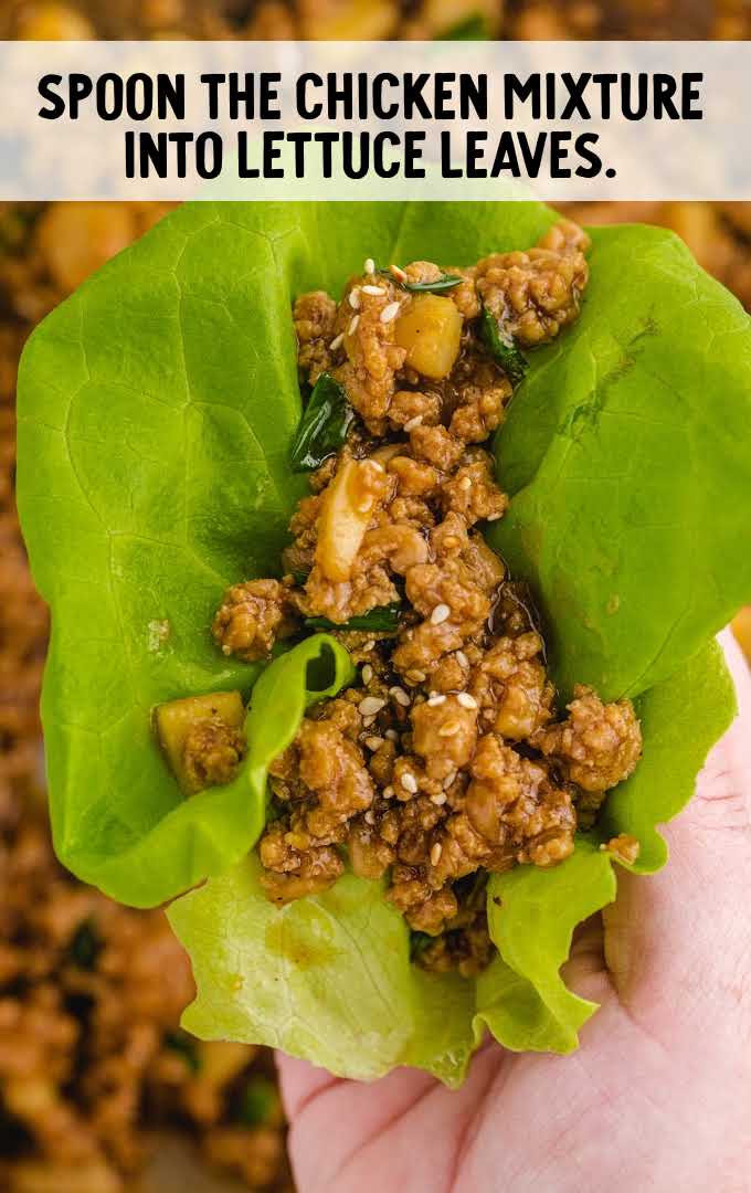 Asian chicken lettuce wrap process shot of chicken mixture being spooned into lettuce leaf