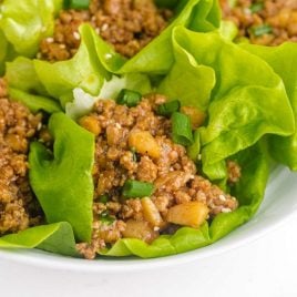 close up shot of Asian chicken lettuce wrap garnished with green onions on a plate