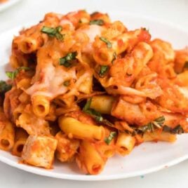 close up shot of a plate of chicken baked ziti garnished with basil
