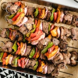 Close-up of beef kabobs on the grill with chunks of steak, green and red bell peppers, and onions