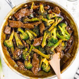 close up overhead shot of Beef and Broccoli in a baking pan with a wooden spoon