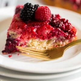 a slice of berry cake on a plate topped with berries and a fork