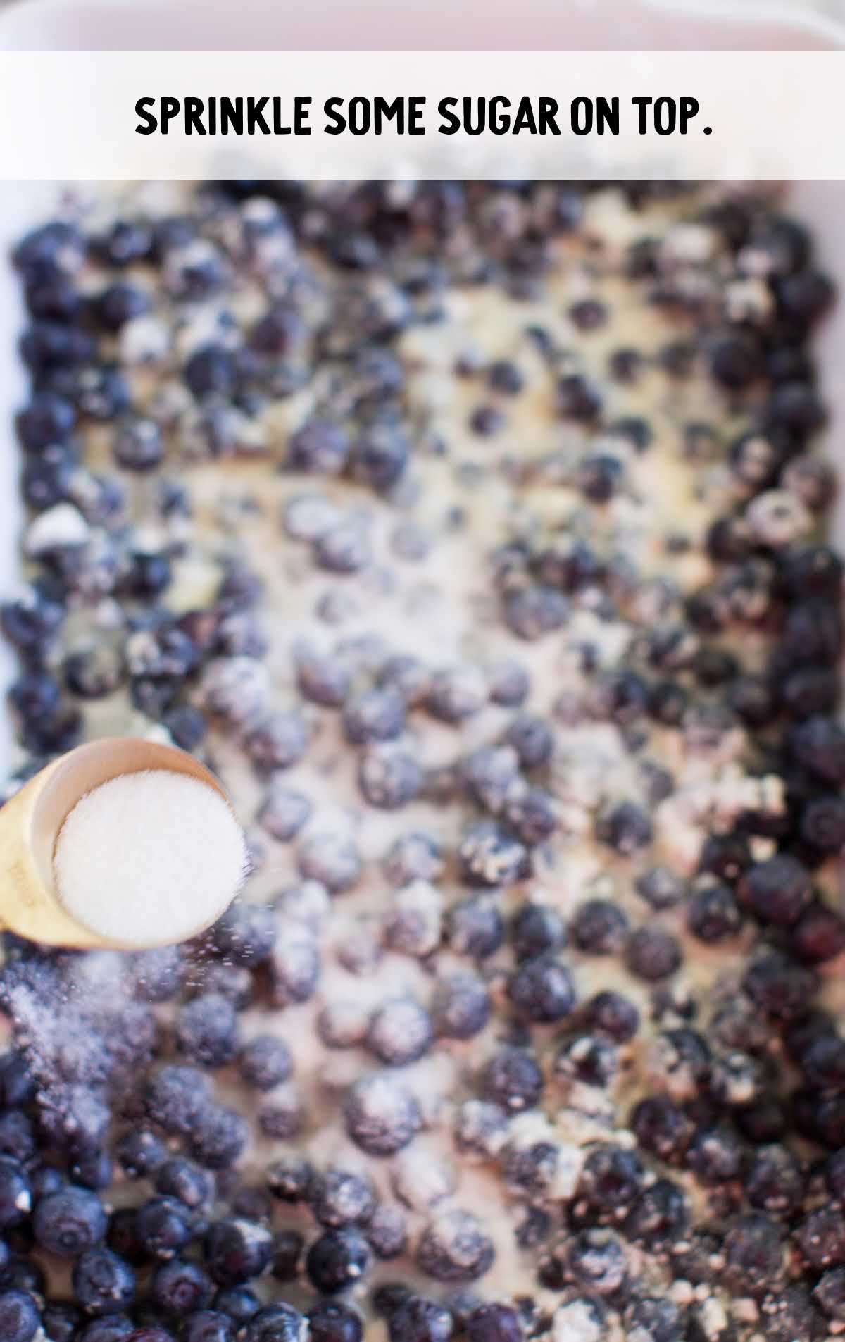 Blueberry Cobbler Recipe process shot of sugar being poured on top the blueberry cobbler