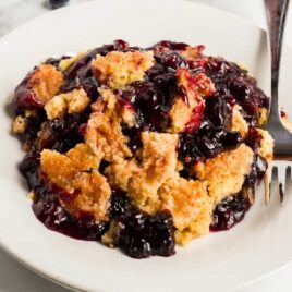 a piece of Blueberry Dump Cake on a plate with a fork