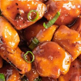 close up overhead shot of bourbon chicken served over white rice and topped with diced green onions