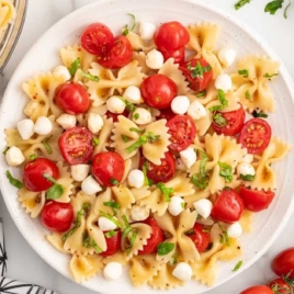 Caprese pasta salad topped with basil on a plate