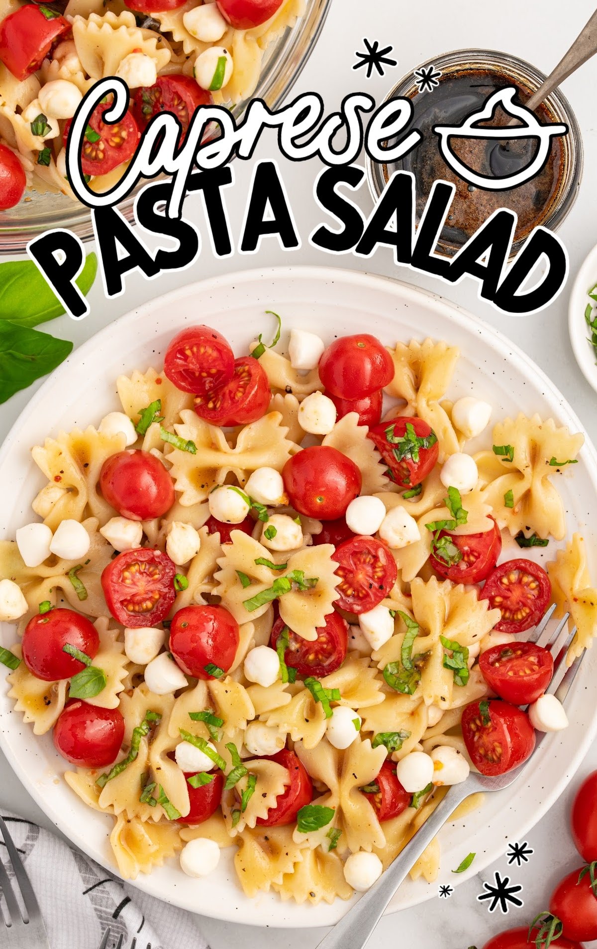 Caprese pasta salad topped with basil on a plate with a fork