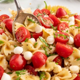 Caprese pasta salad topped with basil in a bowl with a spoon