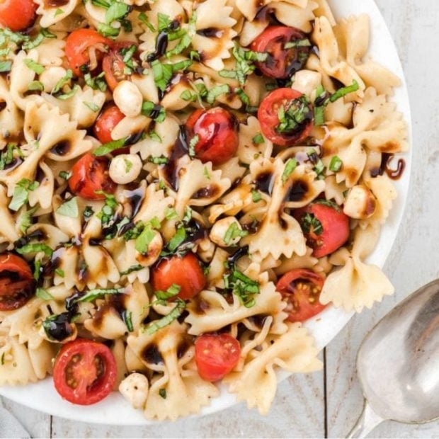 close up overhead shot of Caprese pasta salad topped with balsamic glaze and basil in a bowl