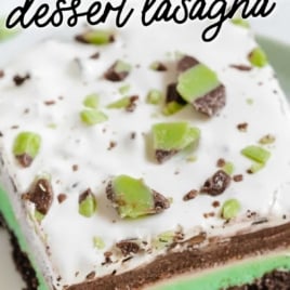 Slice of mint chip dessert lasagna showing layers of Oreo crust, green mint cheesecake, chocolate pudding, and whipped topping with mint chocolate pieces