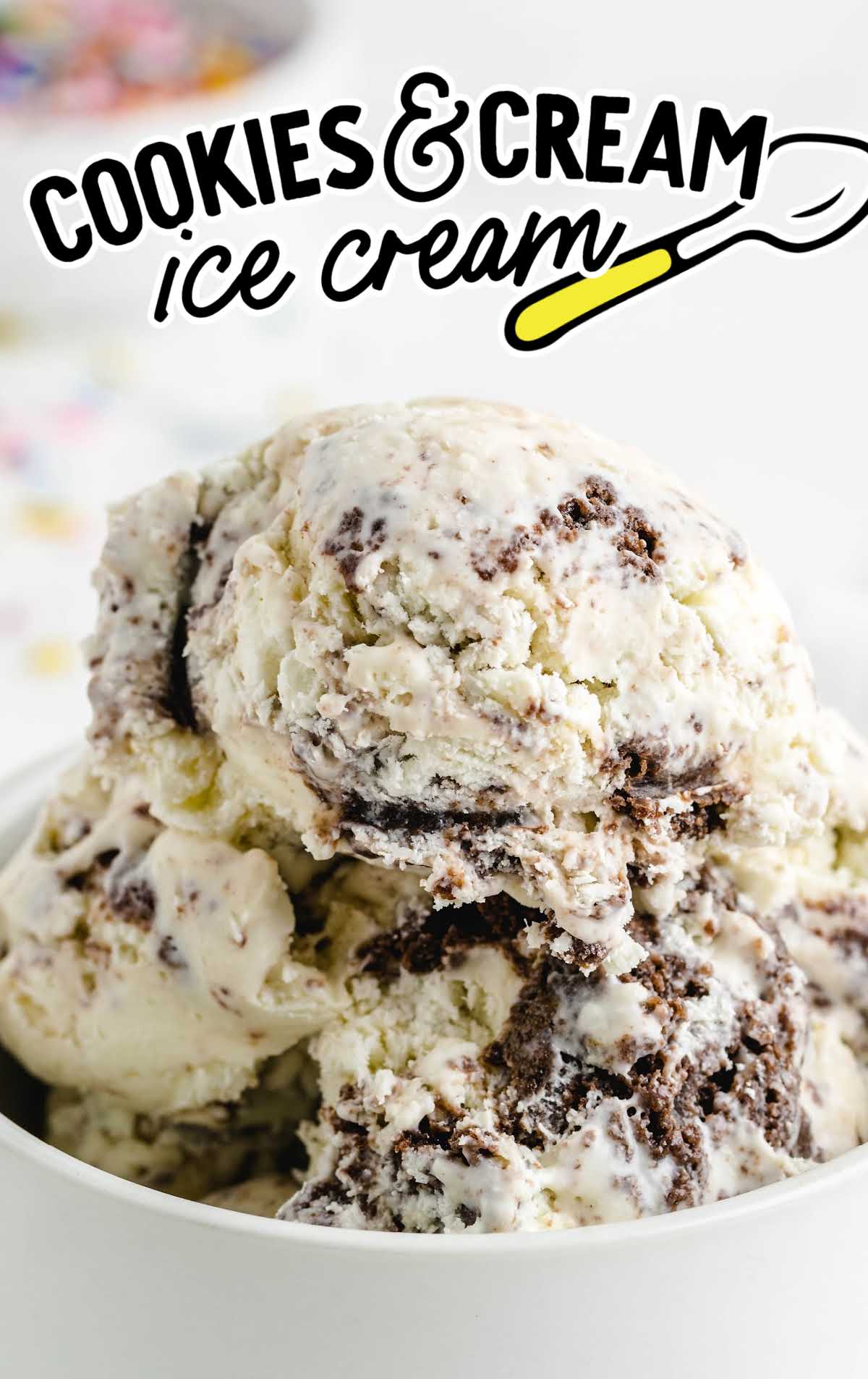 Scoops of creamy cookies and cream ice cream in a white bowl with swirls of chocolate cookies.