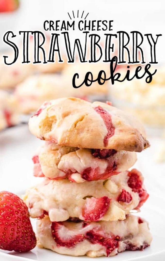 close up shot of cream cheese strawberry cookies stacked on top of each other on a white plate with strawberries
