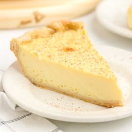 Slice of baked custard pie on a plate, showcasing its smooth texture and flaky crust