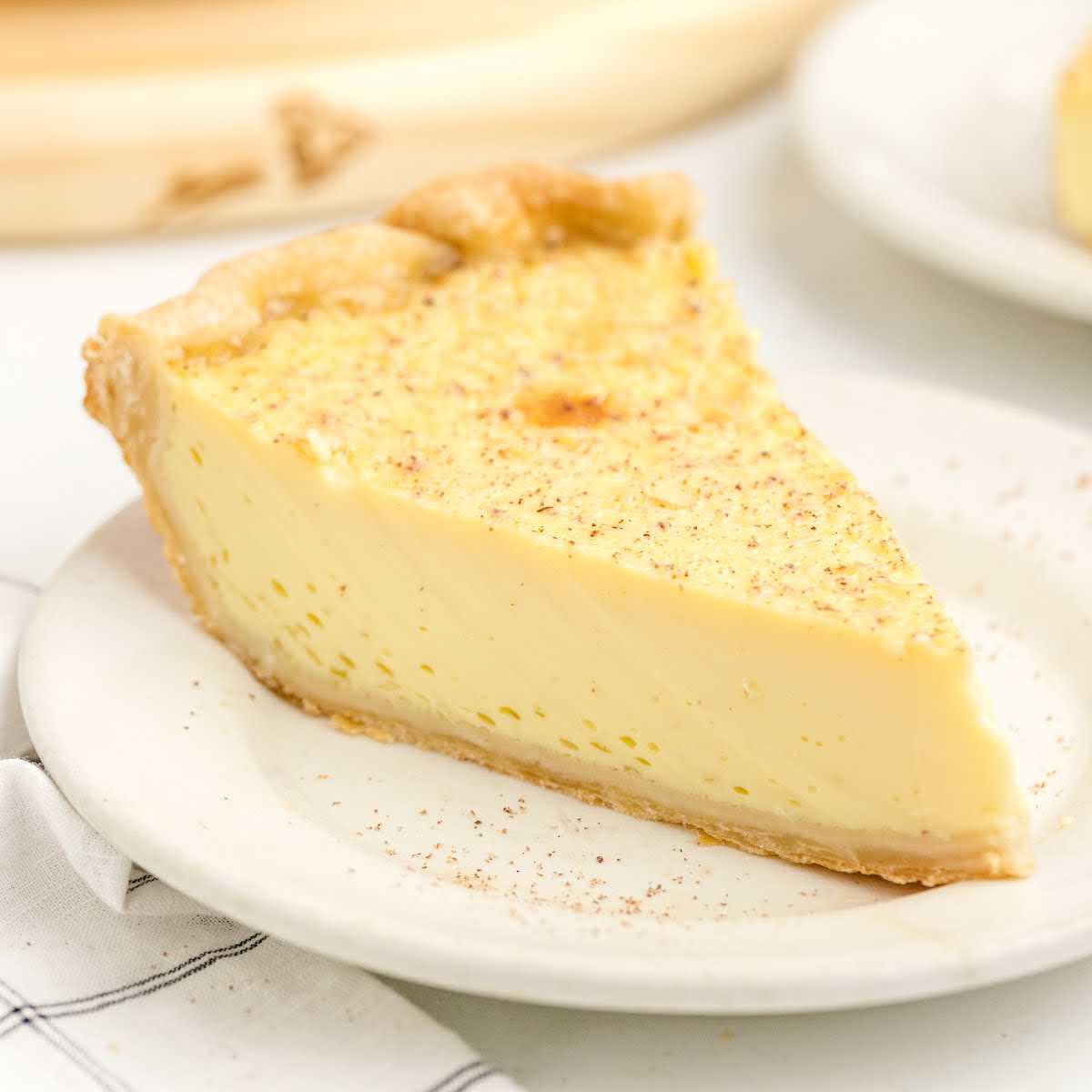 Slice of baked custard pie on a plate, showcasing its smooth texture and flaky crust