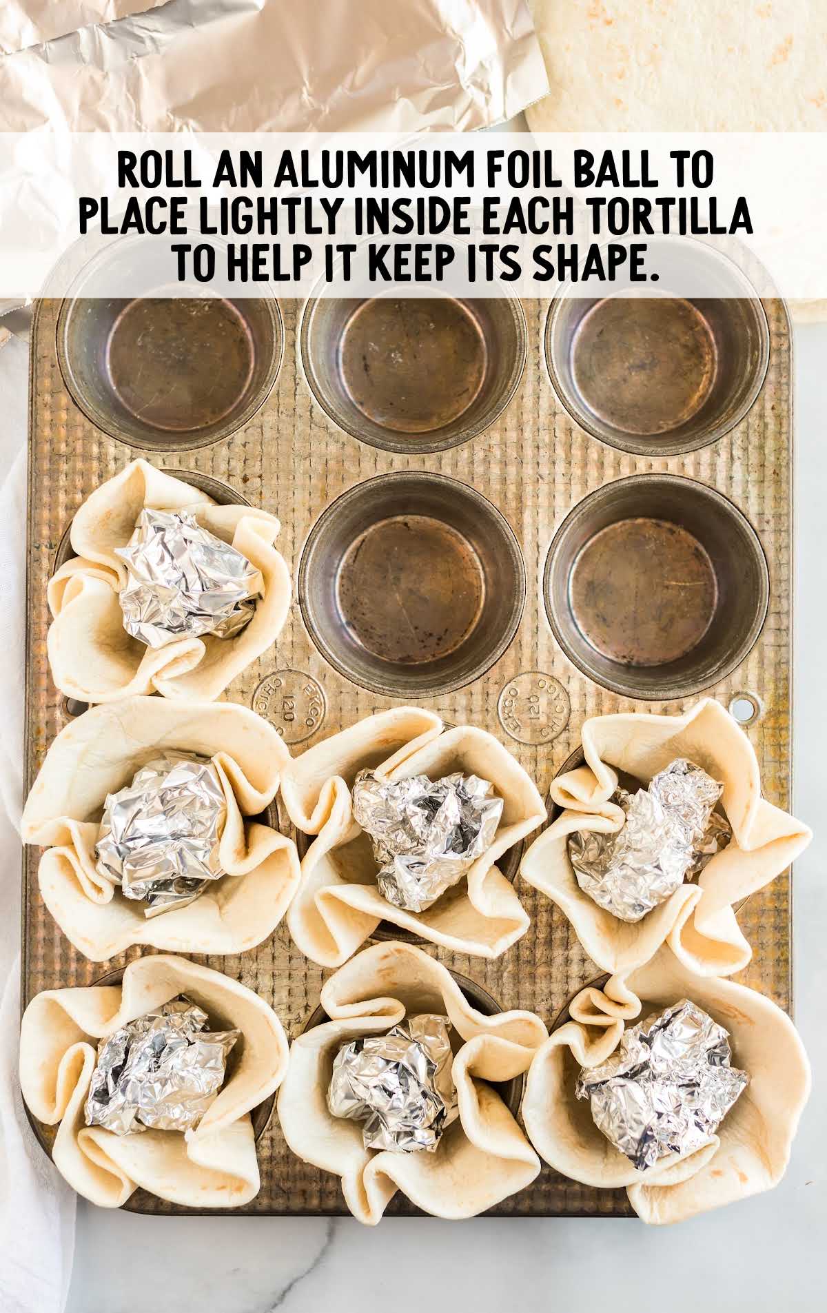tortillas filled with balls of aluminum foil in a muffin pan