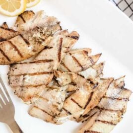 close shot of a plate of grilled tilapia with slices of lemon