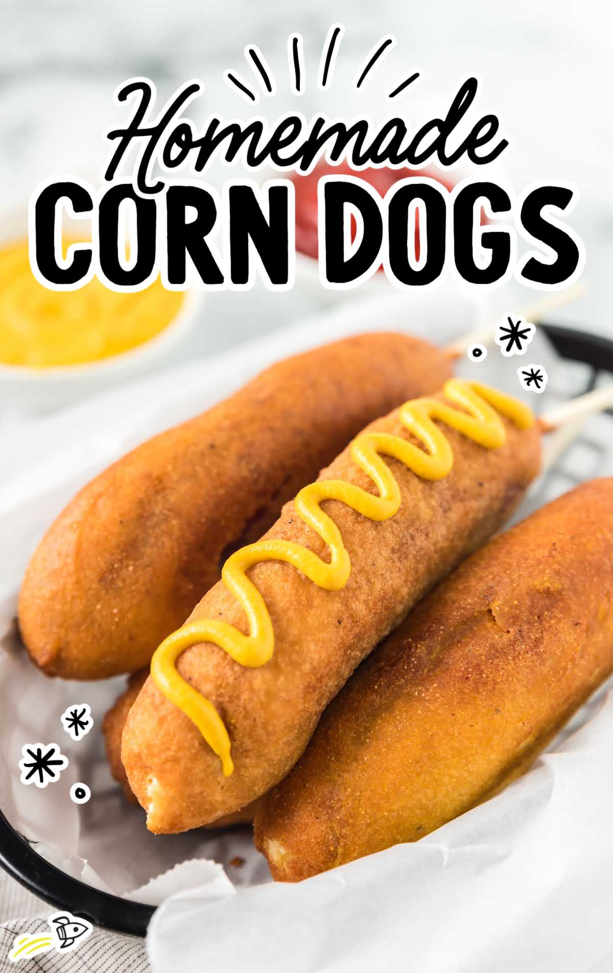 corn dogs in a basket topped with mustard