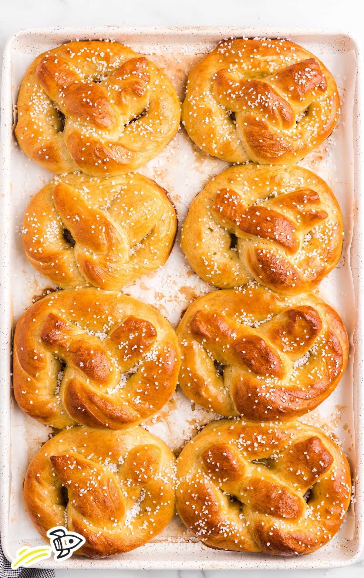 close up overhead shot of homemade soft pretzels topped with kosher salt in a tin pan