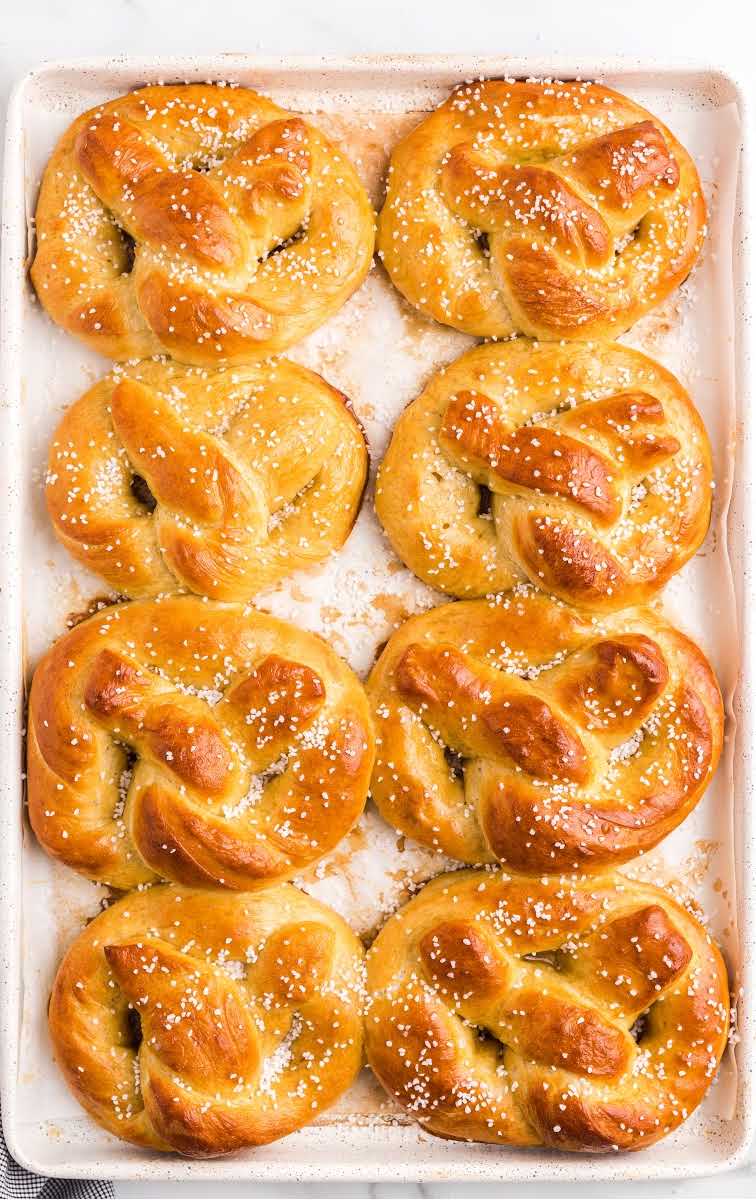 close up overhead shot of homemade soft pretzels topped with kosher salt in a tin pan