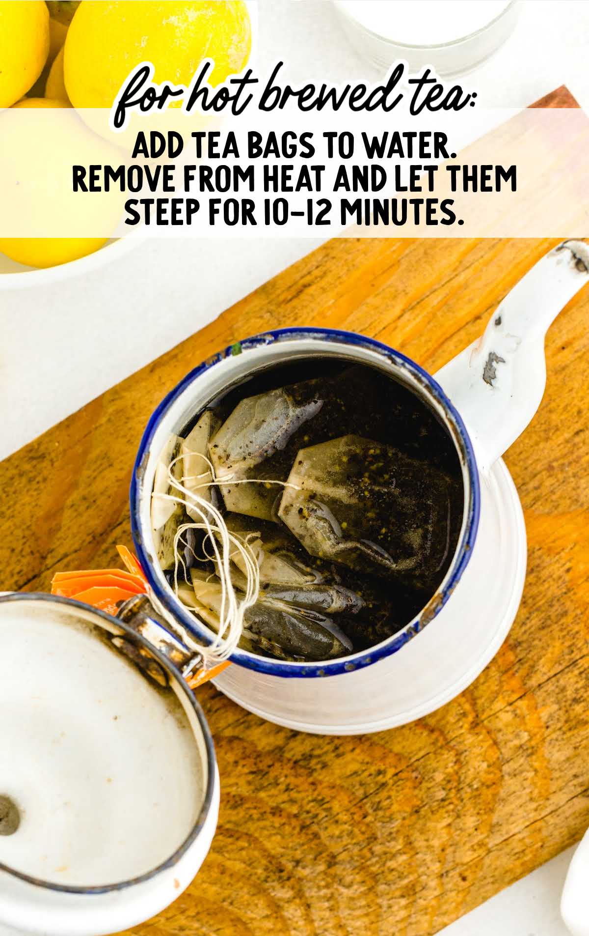 Top view of a small enamel pot filled with tea bags steeping in hot water, with instructions for making hot brewed tea written above