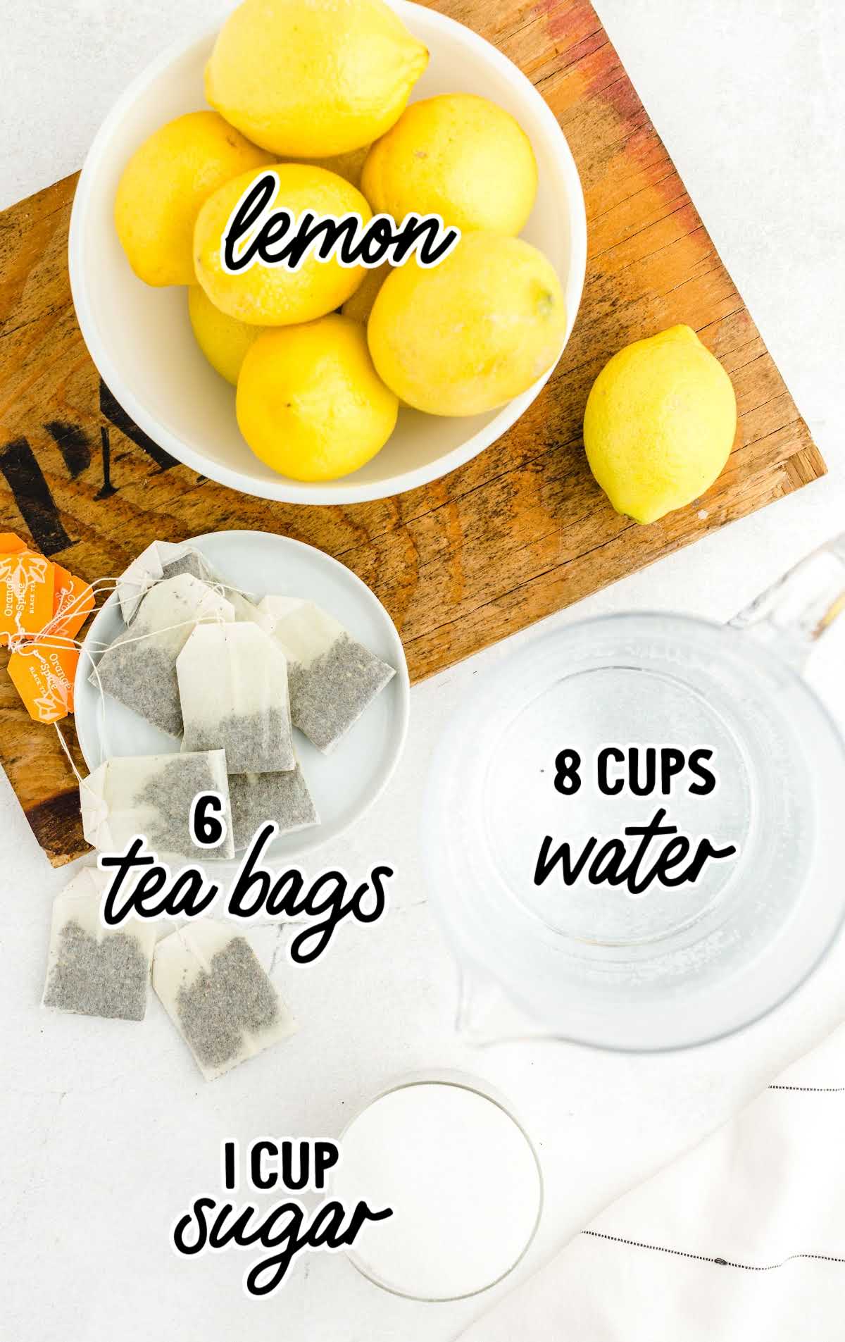 Flat lay of iced tea ingredients including lemons, tea bags, sugar, and water labeled for clarity
