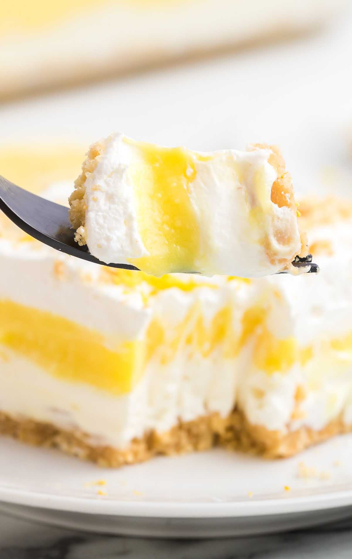 close up shot of a slice of lemon lasagna with a piece taken out of it on a fork