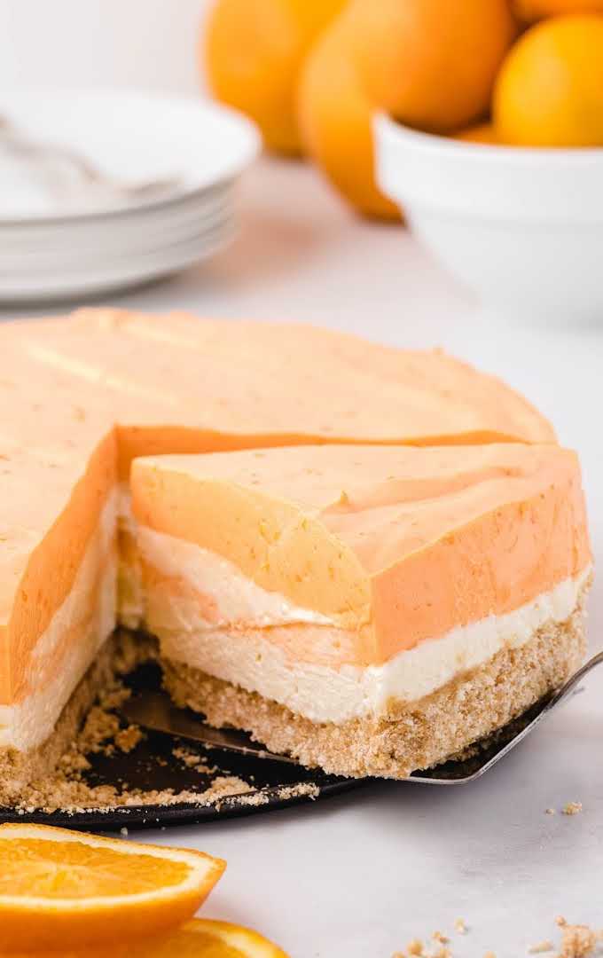 close up shot of no-bake orange creamsicle cheesecake with a slice being taken out of it