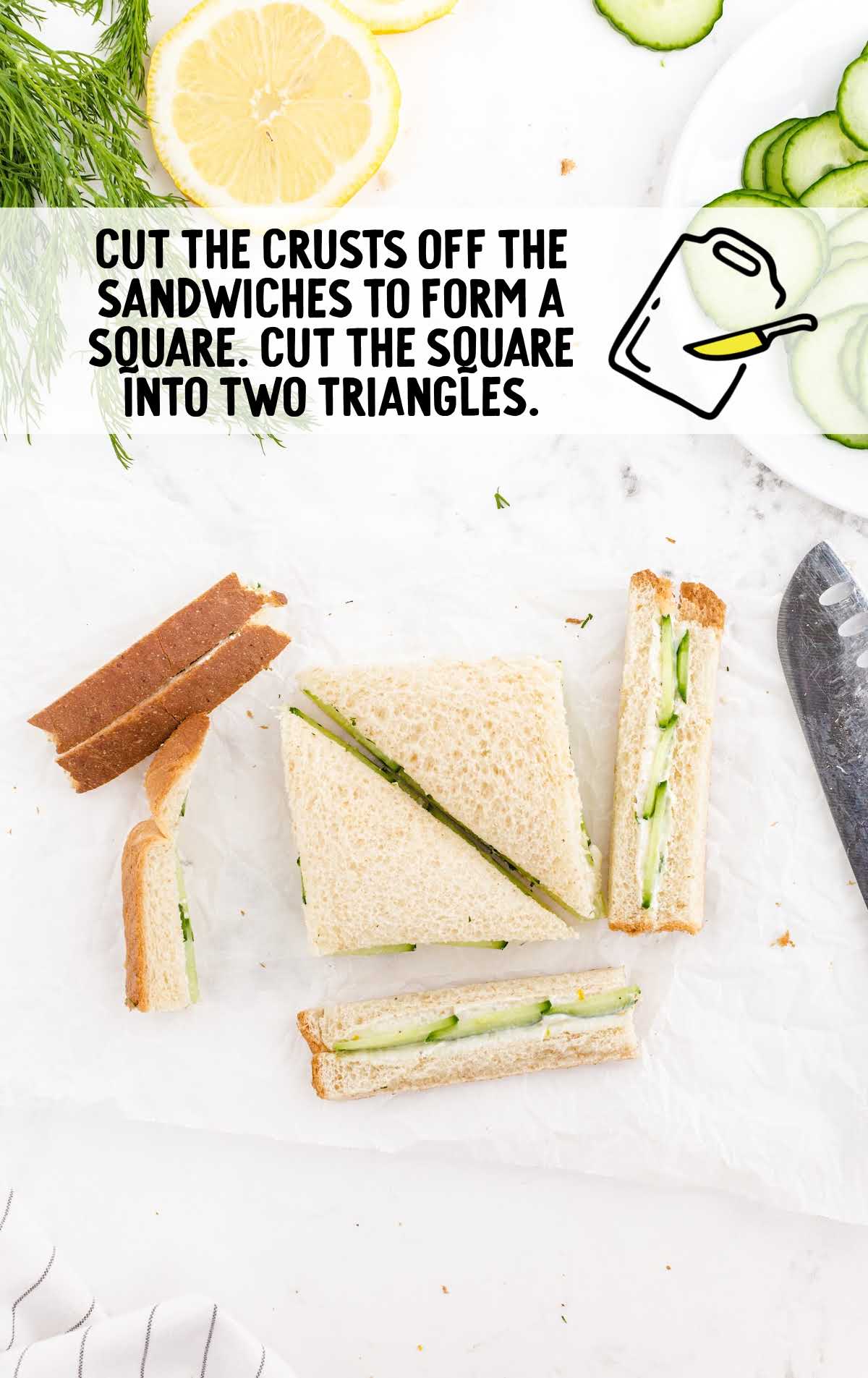Overhead view of a cucumber sandwich being trimmed and cut—crusts removed to form a square, then sliced diagonally into triangles, with text instructions and garnish of lemon and dill nearby.