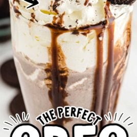 close up shot of a glass of Oreo milkshake topped with a Oreo and chocolate glaze falling down the cup