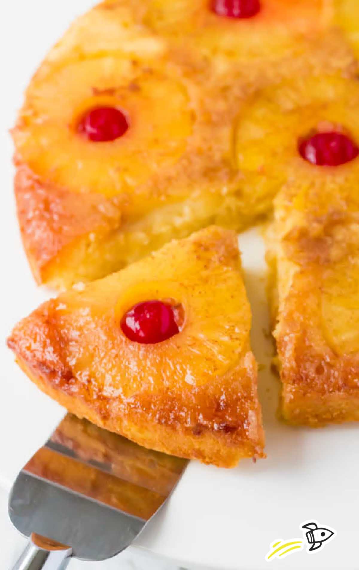 a close up shot of a slice of Pineapple Upside Down Cake being taken out with a spatula