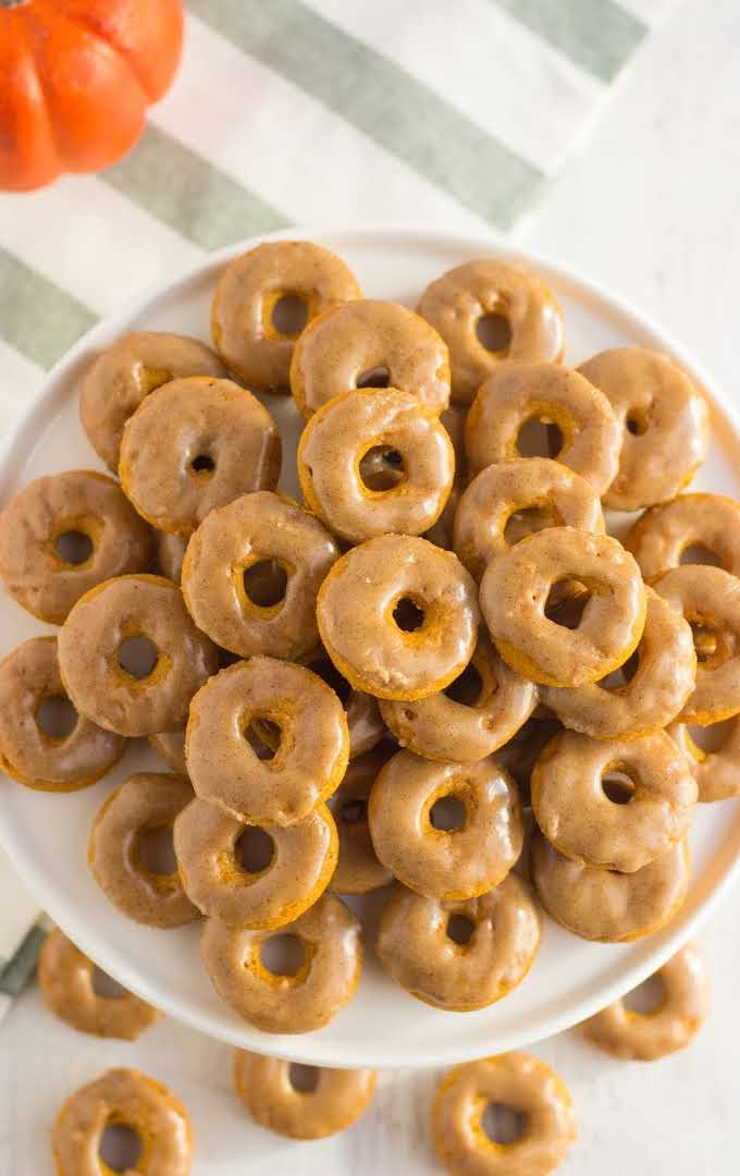 close up overhead shot of pumpkin donuts stacked on top of each other on a plate