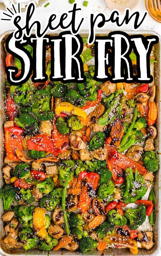 close up overhead shot of sheet pan stir fry topped with sesame seeds and sauce in a sheet pan